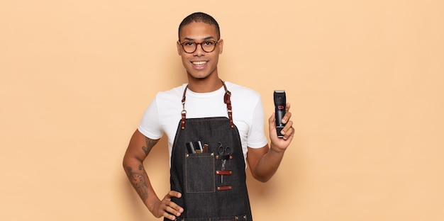 young black man smiling happily with a hand on hip and confident, positive, proud and friendly attitude