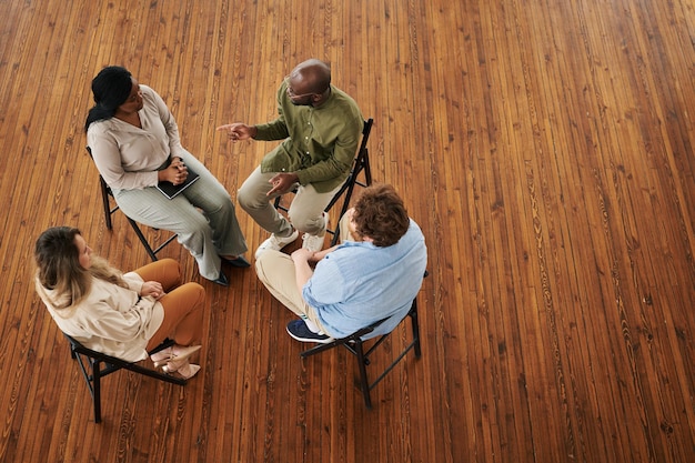 Young black man talking to one of patients attending psychotherapy course