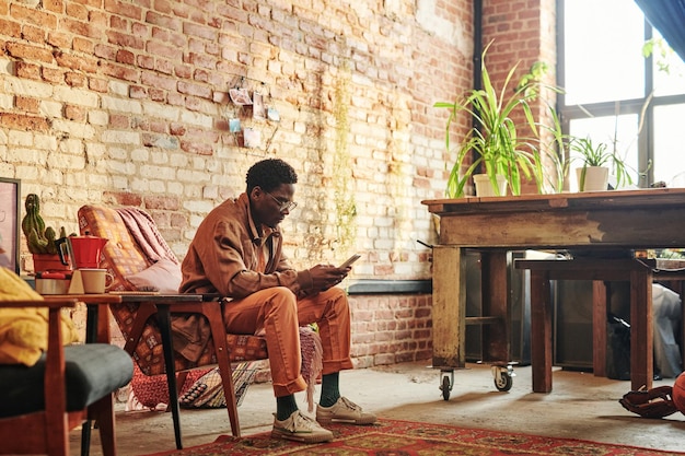 Young black man texting in his smartphone or communicating in video chat