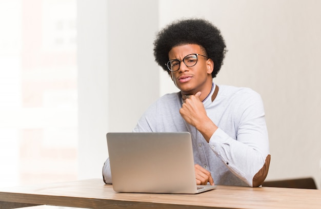 Young black man using his laptop coughing, sick due a virus or infection