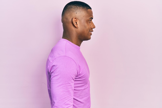 Young black man wearing casual pink sweater looking to side, relax profile pose with natural face and confident smile.