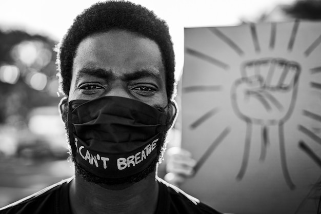 Young black man wearing face mask during equal rights\
protest