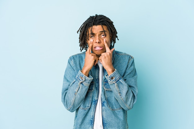 Young black man wearing a jeans jacket crying, unhappy with something, agony and confusion concept.