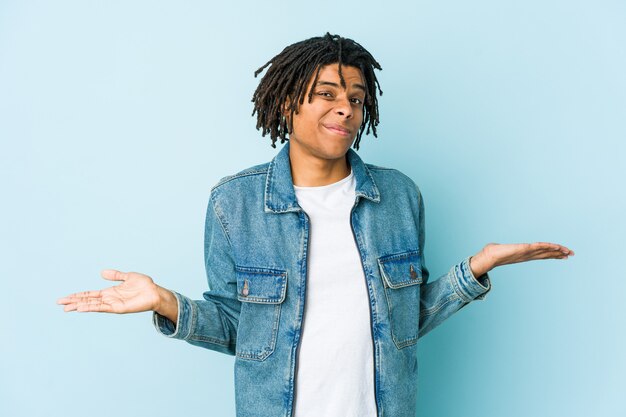 Young black man wearing a jeans jacket doubting and shrugging shoulders in questioning gesture.