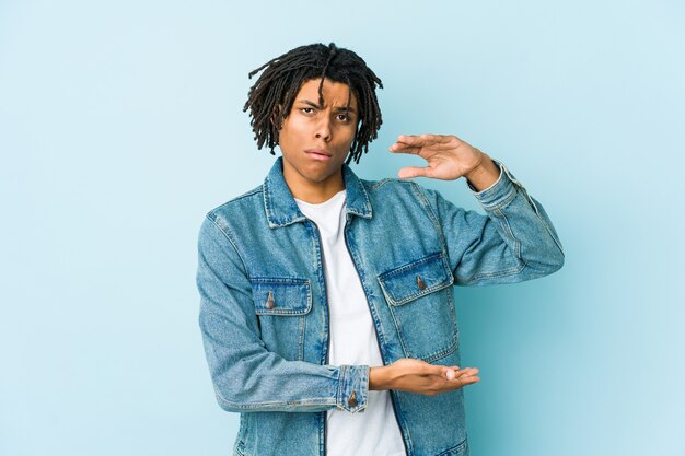 Young black man wearing a jeans jacket holding something with both hands, product presentation.