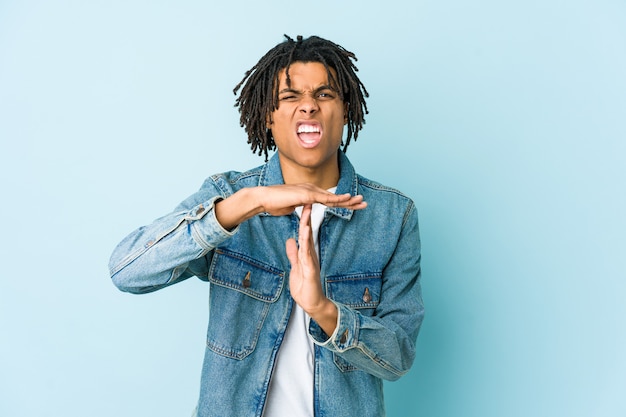 Young black man wearing a jeans jacket showing a timeout gesture.