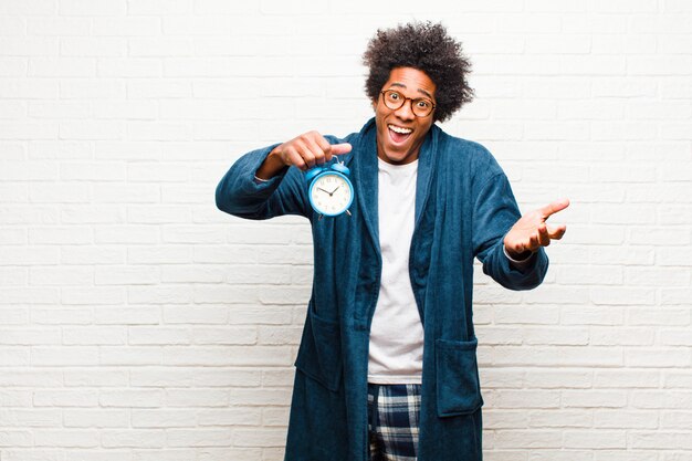 Young black man wearing pajamas with an alarm clock