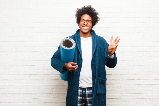 Young black man wearing pajamas  with a yoga mat 