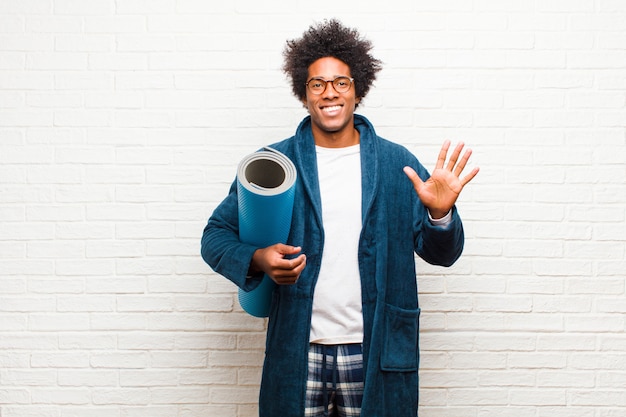 Young black man wearing pajamas  with a yoga mat