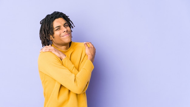 Young black man wearing rasta hairstyle hugs, smiling carefree and happy.