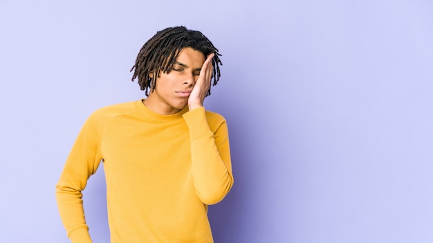 Young black man wearing rasta hairstyle who is bored, fatigued and need a relax day.