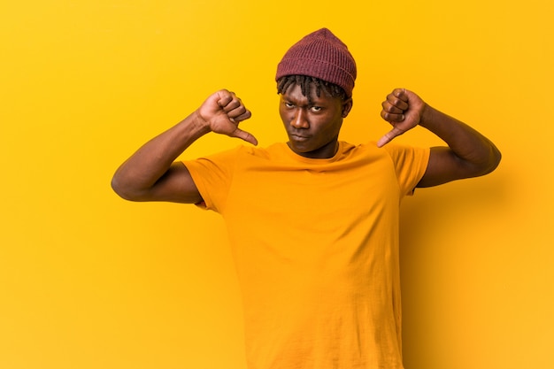 Young black man wearing rastas over yellow background feels proud and self confident, example to follow.