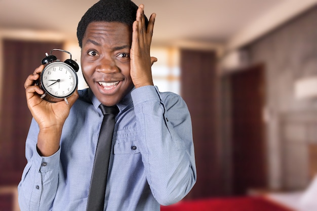 Young black man with alarm clock