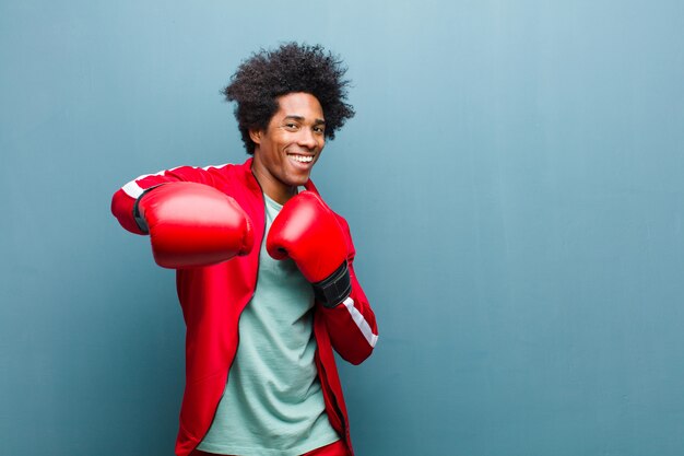 Young black man with boxing gloves against blue grunge wall