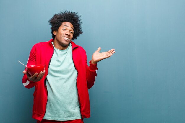 Young black man with a breakfast bowl against blue grunge wall