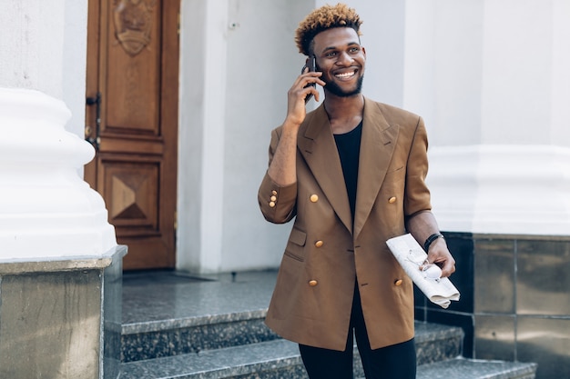 Young black man with phone and newspaper