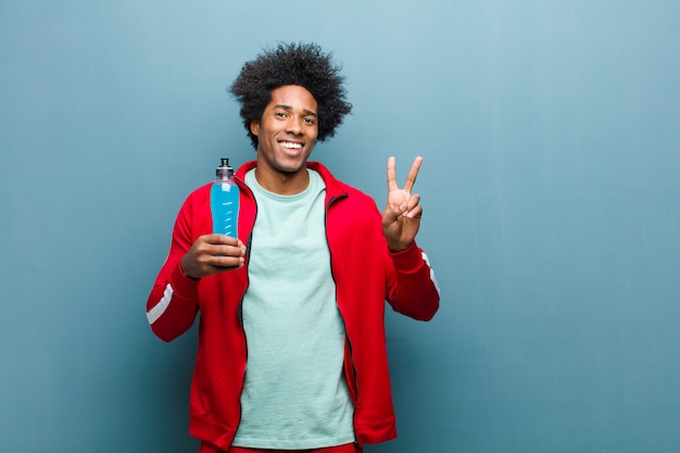 Young black man with a sport drink   blue grunge wall