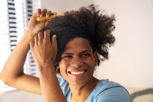 Фото Молодой темнокожий человек ухаживает за афро-волосами