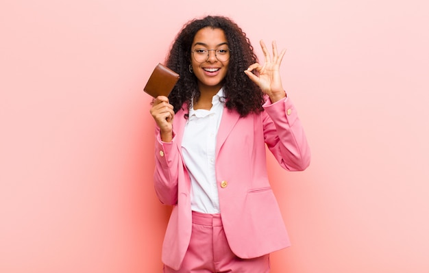 Young black pretty business woman with a wallet against pink wall