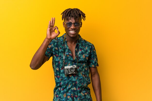 Young black rasta man wearing a vacation look cheerful and confident showing ok gesture.