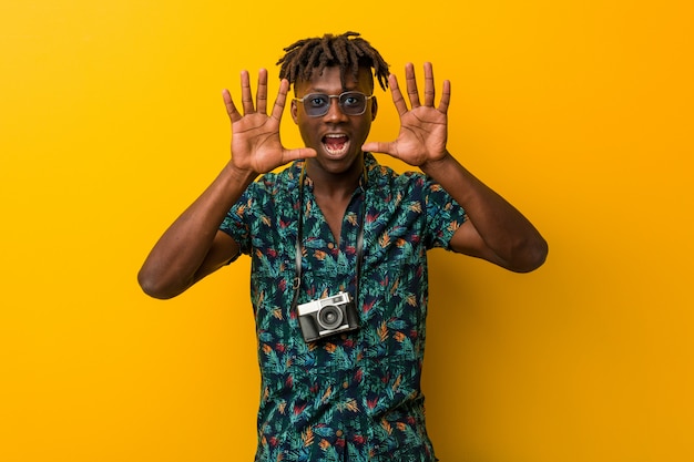 Young black rasta man wearing a vacation look showing number ten with hands.