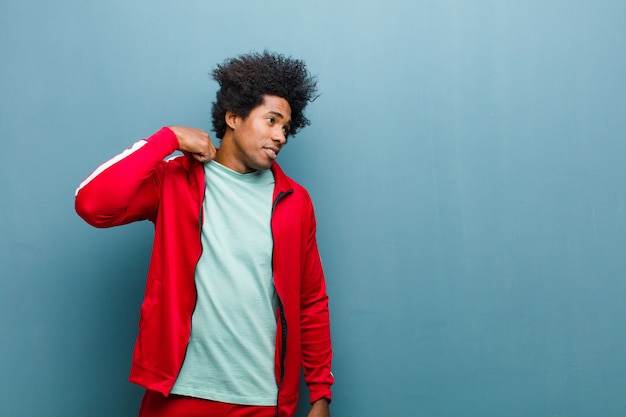 Young black sports man feeling stressed, anxious, tired and frustrated, pulling shirt neck, looking frustrated with problem against grunge wall