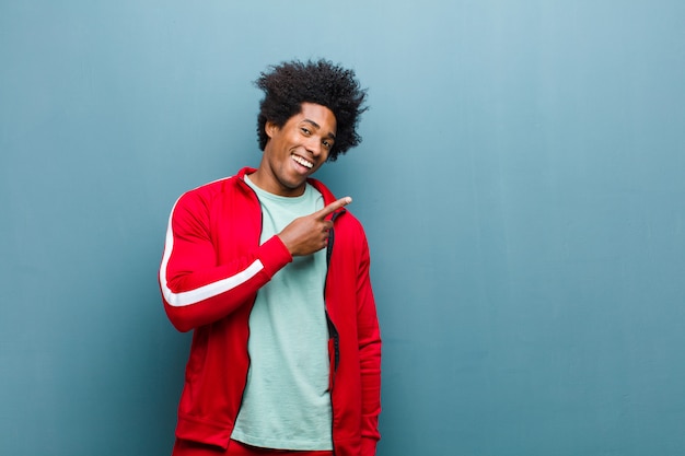 Young black sports man looking excited and surprised pointing to the side and upwards to copy space