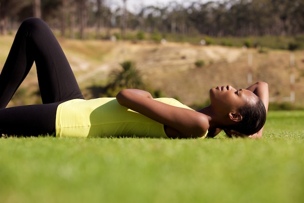 Young black sports woman lying down on grass