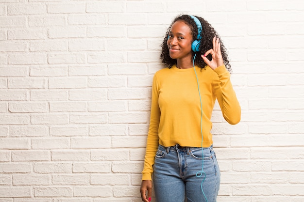 Young black woman cheerful and confident doing ok gesture, excited and screaming