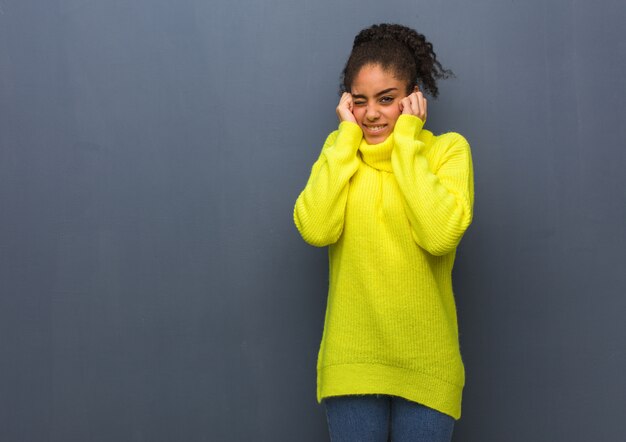 Young black woman covering ears with hands