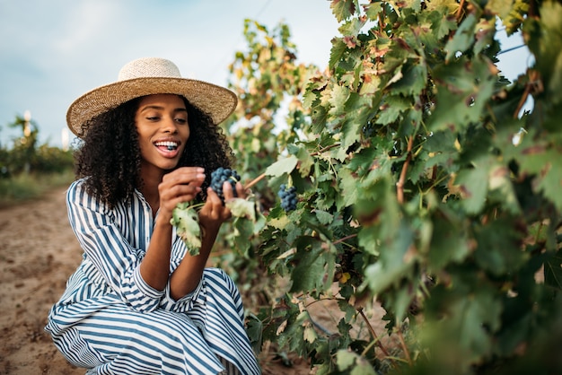 Young black woman eating a grape in a vineyard