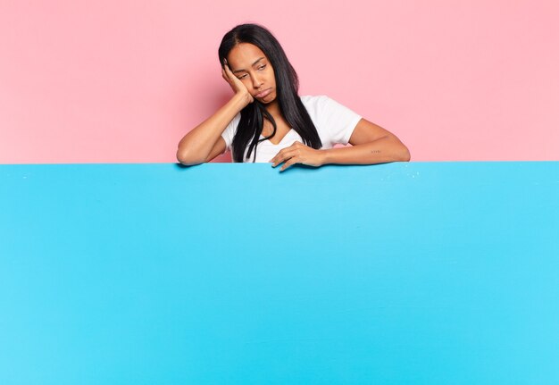 Young black woman feeling bored, frustrated and sleepy after a tiresome, dull and tedious task, holding face with hand. copy space concept