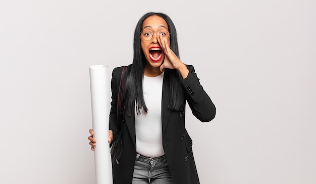 Young black woman feeling happy, excited and positive, giving a big shout out with hands next to mouth