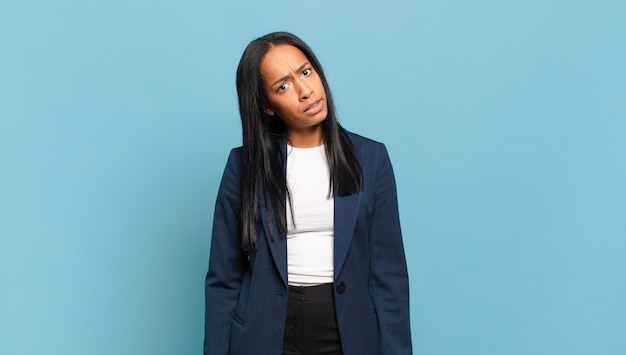 Young black woman feeling puzzled and confused, with a dumb, stunned expression looking at something unexpected. business concept