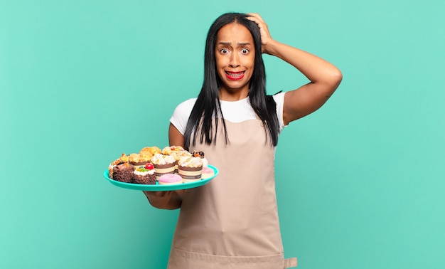 Young black woman feeling stressed, worried, anxious or scared, with hands on head, panicking at mistake. bakery chef concept