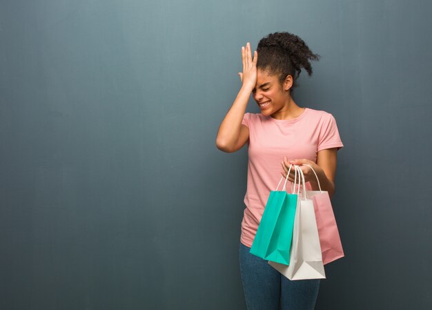 Young black woman forgetful, realize something. She is holding a shopping bags.