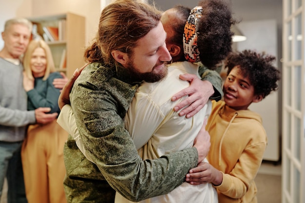 Young black woman giving hug to her husband in camouflage uniform