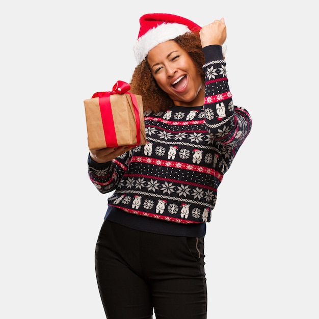 Young black woman holding a gift in christmas day who does not surrender