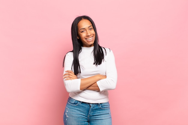 Young black woman looking like a happy, proud and satisfied achiever smiling with arms crossed