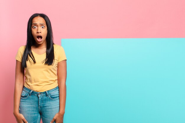 Young black woman looking very shocked or surprised, staring with open mouth saying wow