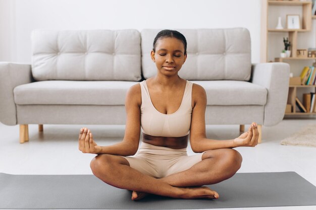 Young black woman meditating at home yoga online concept free space