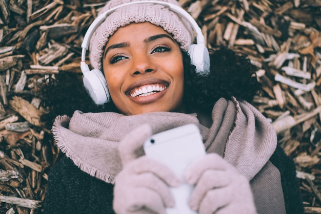 Giovane donna di colore sul telefono cellulare che si trova sulle paci di legno