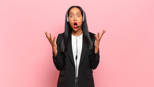 Young black woman open-mouthed and amazed, shocked and astonished with an unbelievable surprise. telemarketing concept