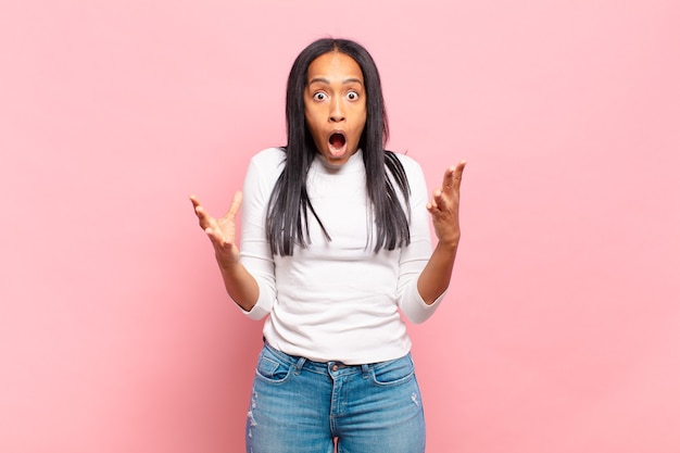 Young black woman open-mouthed and amazed, shocked and astonished with an unbelievable surprise