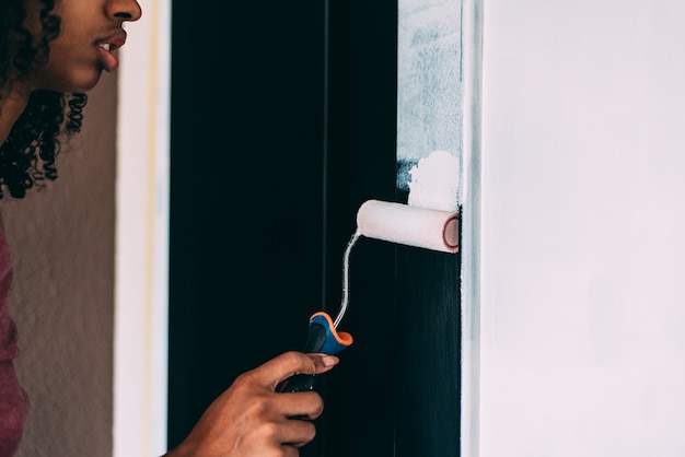 Young black woman painting a wardrobe