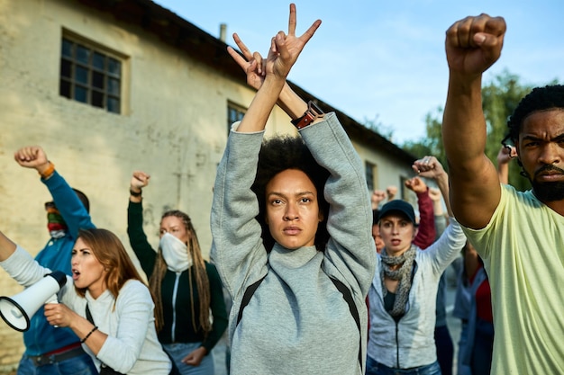 Giovane donna di colore che partecipa a manifestazioni pubbliche e mostra un gesto di pace sopra la sua testa