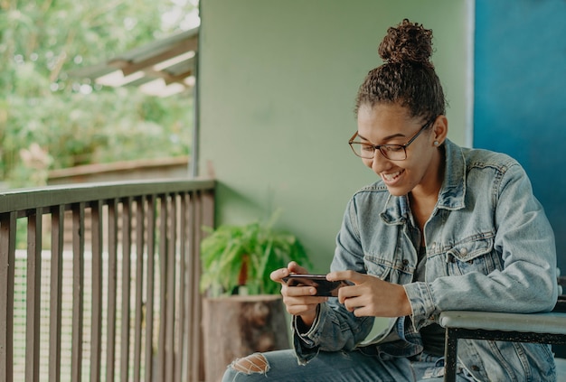 Young black woman playing or chatting with her smartphone.