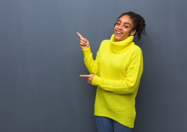 Young black woman pointing to the side with finger