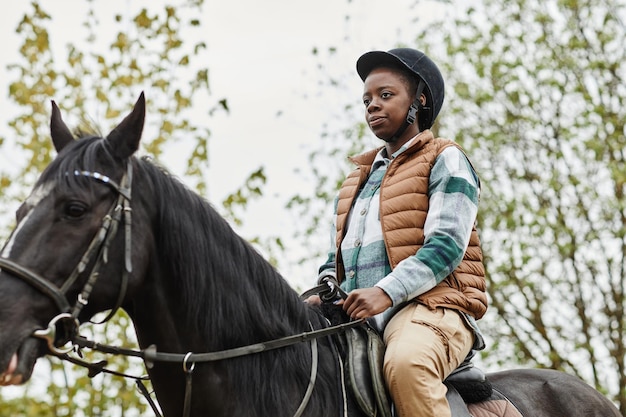屋外で馬に乗る若い黒人女性