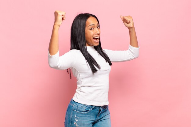 Young black woman shouting triumphantly, looking like excited, happy and surprised winner, celebrating